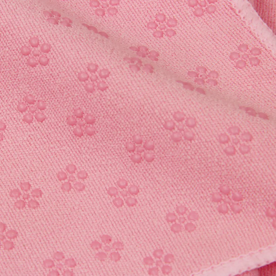 Gros plan sur la surface du tapis de yoga Carnegie 180x60 cm rose, en microfibre avec des picots antidérapants en silicone en forme de fleurs, offrant une excellente adhérence pour le fitness ou le yoga.