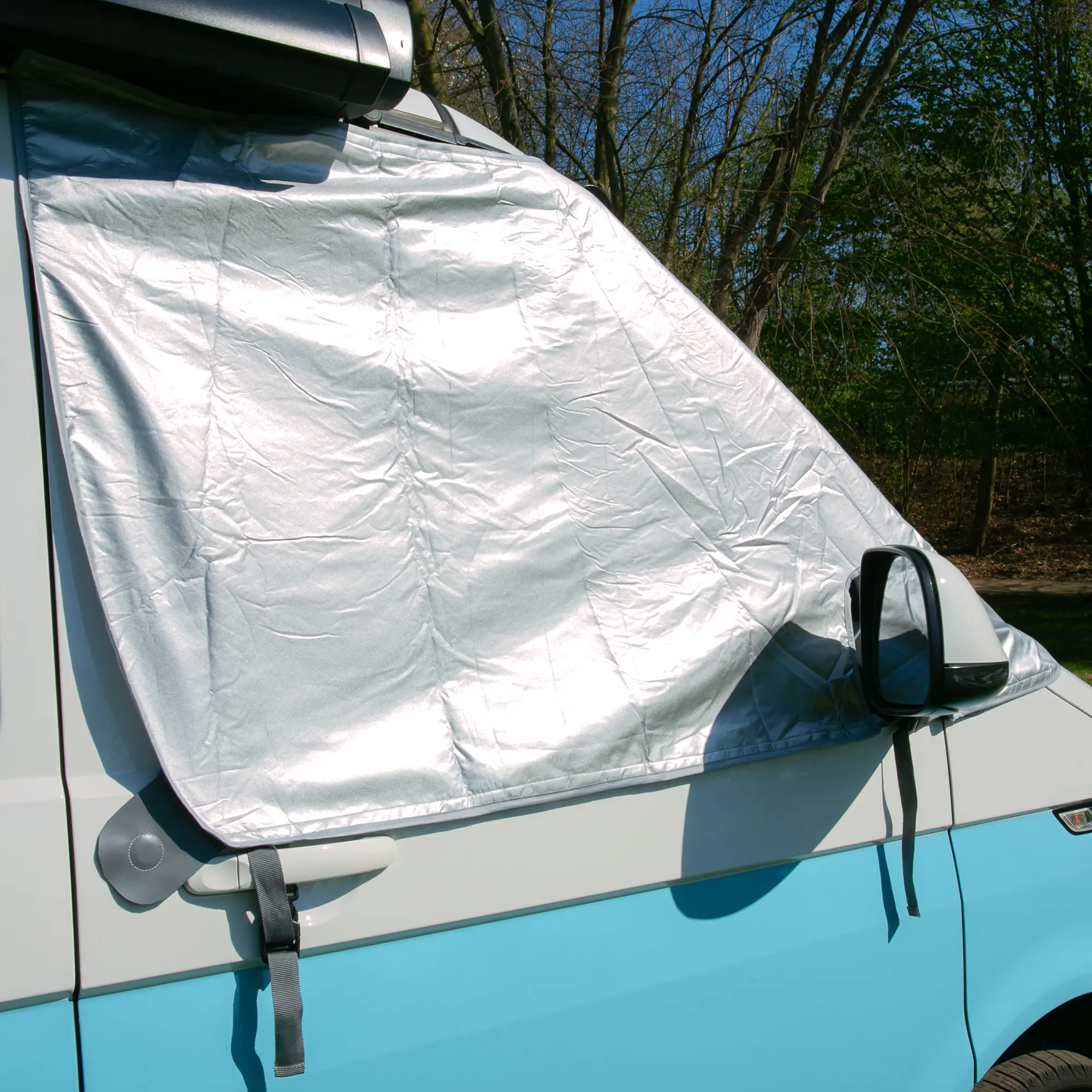 Sonnenschutzmatte your GEAR Sanremo aus silbernem, reflektierendem Material auf der Fahrer-Seitenscheibe eines VW T5/T6, bietet vollständigen Sicht- und Hitzeschutz, passgenau befestigt am Fahrzeug.