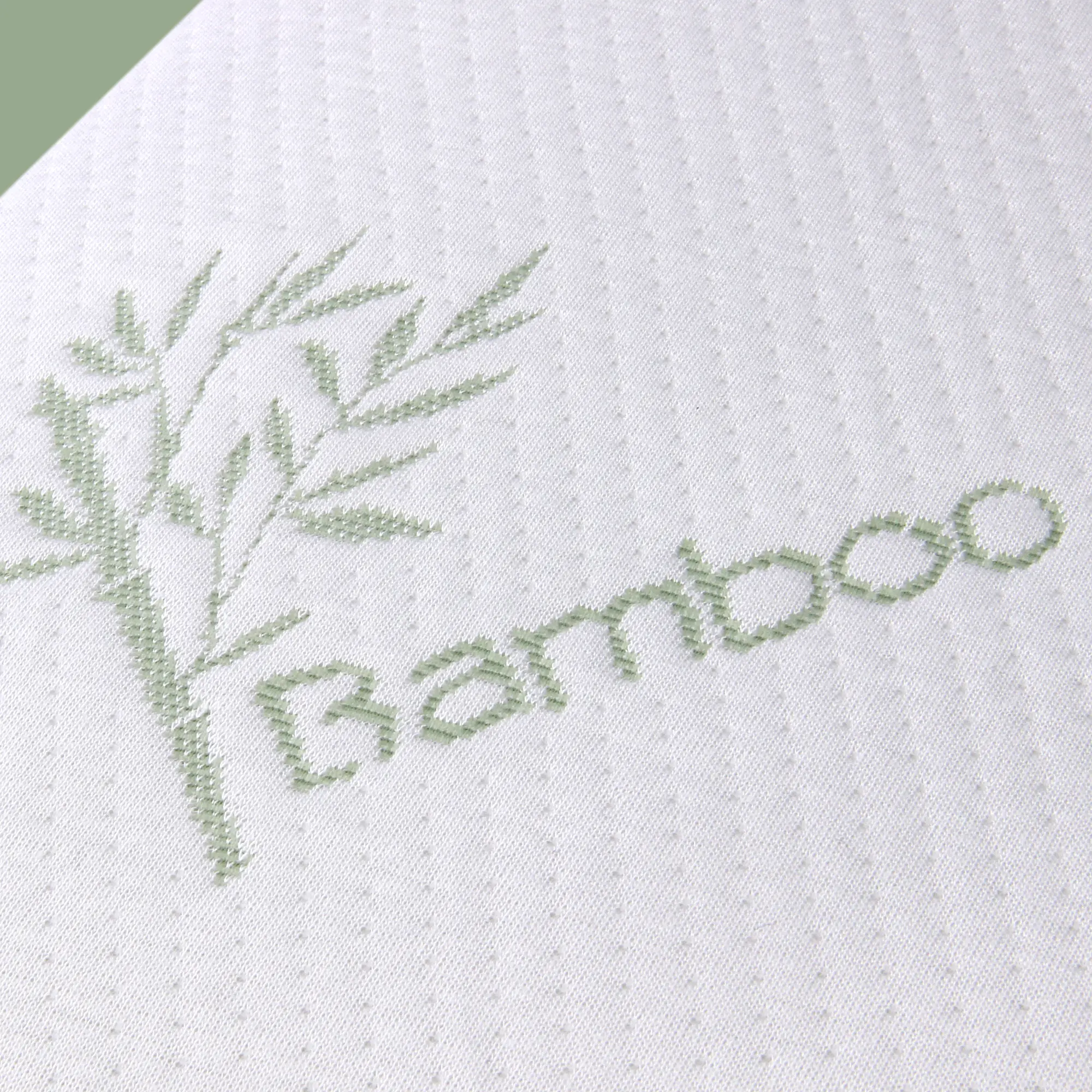Close-up of yourGEAR Bamboo Memory Foam Pillow cover, showing white textured fabric with green bamboo design and "Bamboo" text, highlighting its hypoallergenic bamboo material and ergonomic support.