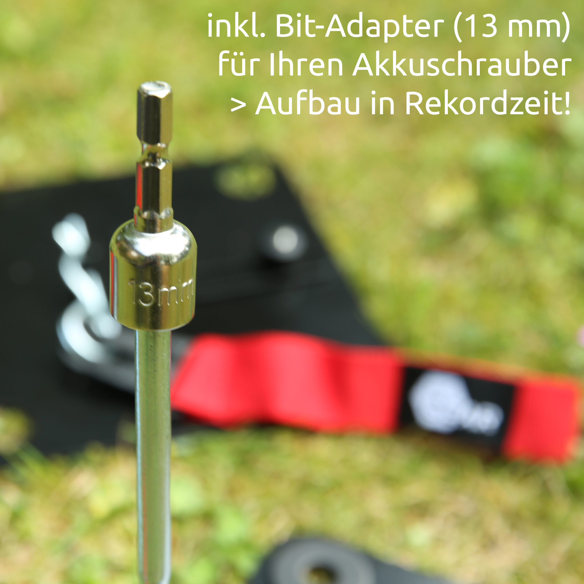 Close-up of shiny 13mm bit adapter mounted on a steel rod, part of the your GEAR Montana awning anchor plate set with blurred black plate and red strap in grass background.