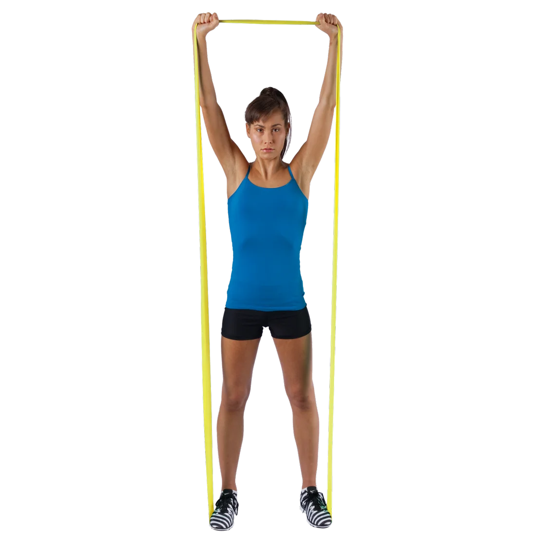 Woman exercising with a yellow Spirit Fitness Band 9 kg, latex-free, 183x10 cm, holding the resistance band overhead while standing, demonstrating its use for strength and rehabilitation training.