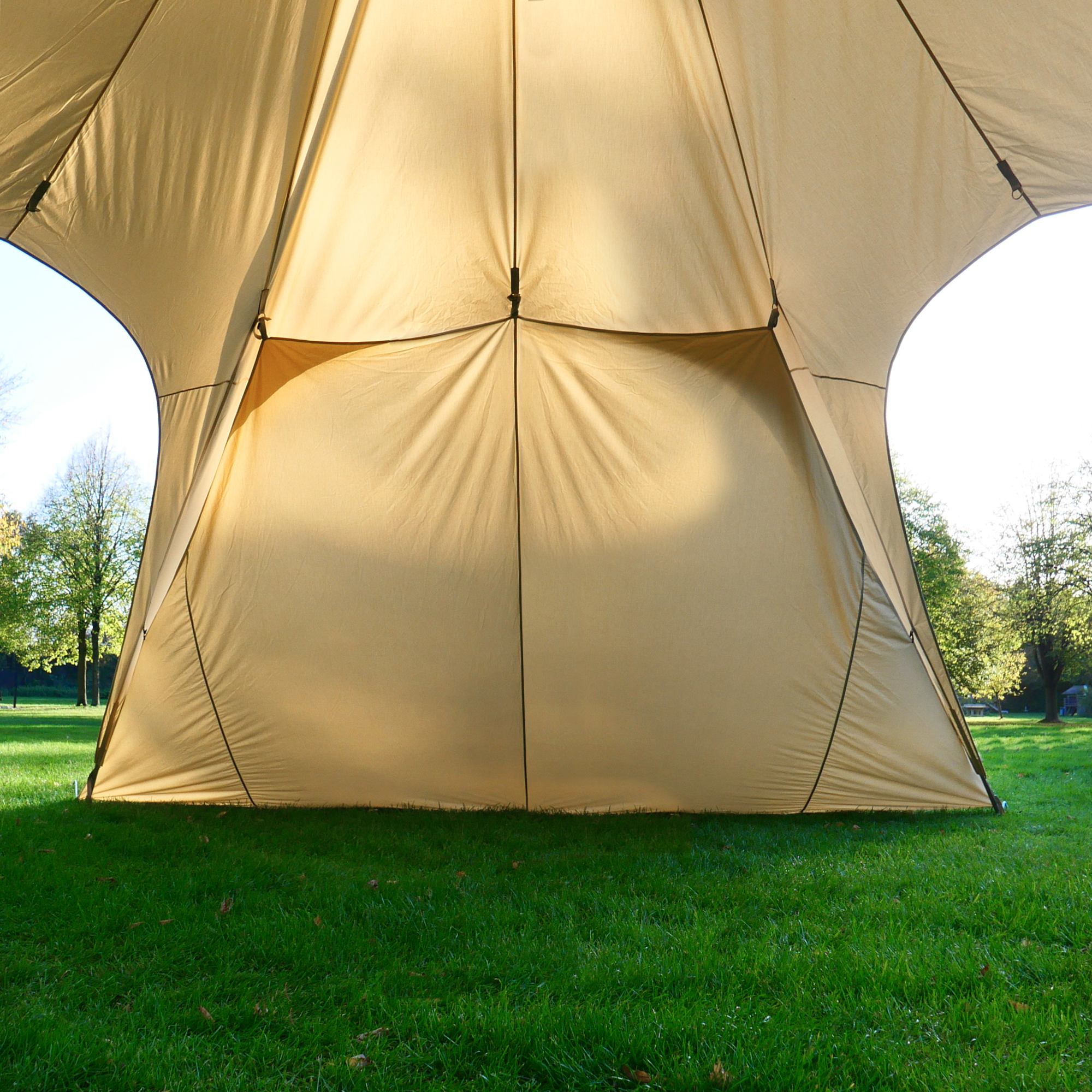 Beige your GEAR Sonora 10 Sidewall attached to a pavilion, made from breathable cotton blend fabric, providing extra sun and wind protection; shown outdoors on a grassy area with clip connections visible.