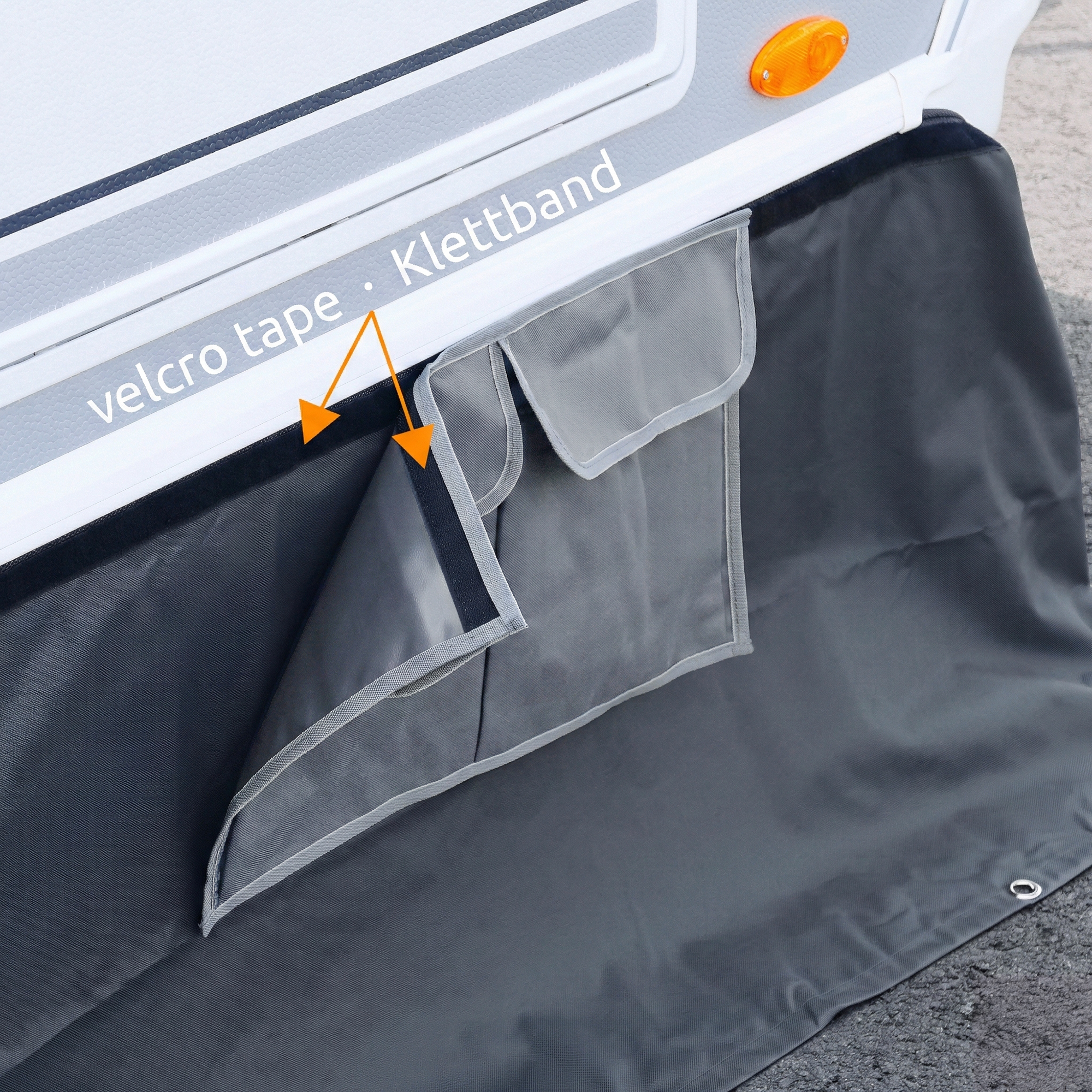 Wohnwagenschürze yourGEAR Draftskirt, 650x60 cm, aus grauem Polyester mit UV-Schutz, zwei Staufächer mit Klettverschluss, montiert an Caravan, ideal als Windschutz und zusätzlicher Stauraum beim Camping.