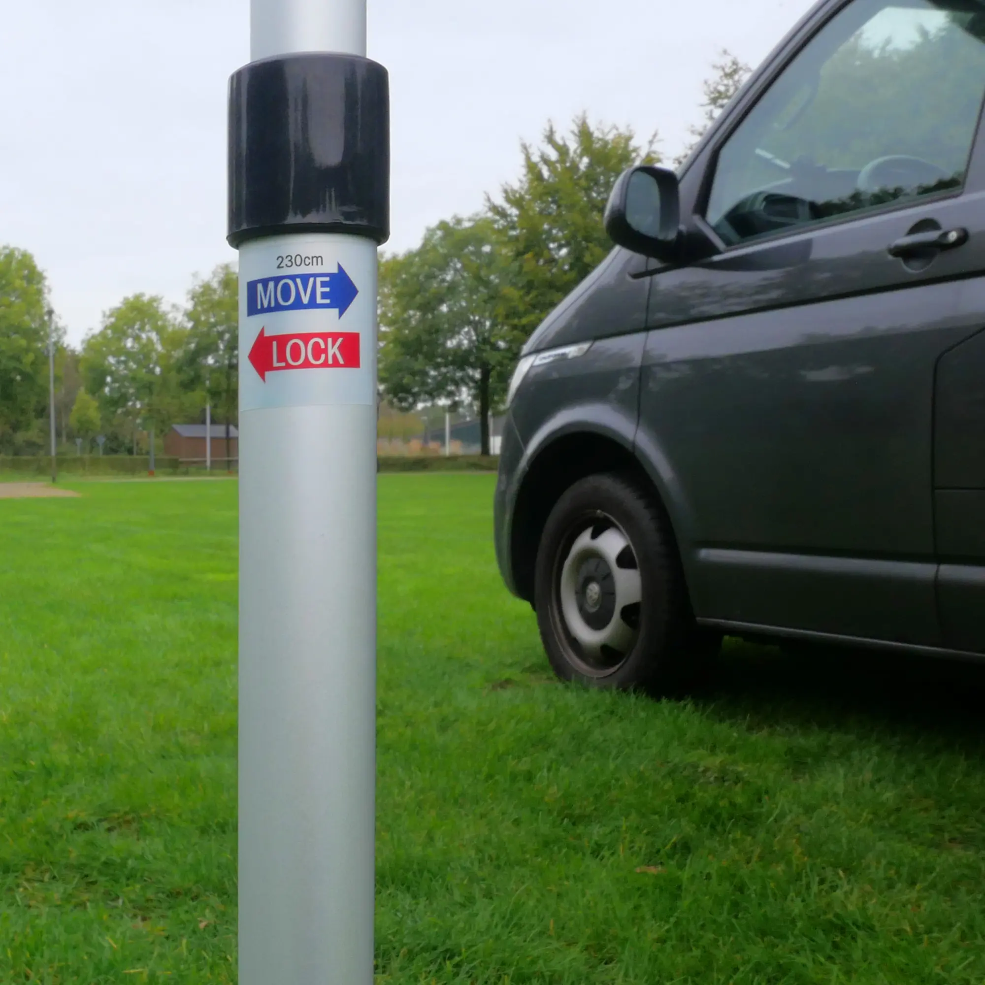Alu-Teleskopstange vom your GEAR Parasol Sonnendach für Bulli und Wohnmobil, Nahaufnahme mit MOVE/LOCK-Hinweis, im Hintergrund ein grauer Campingbus auf einer grünen Wiese.