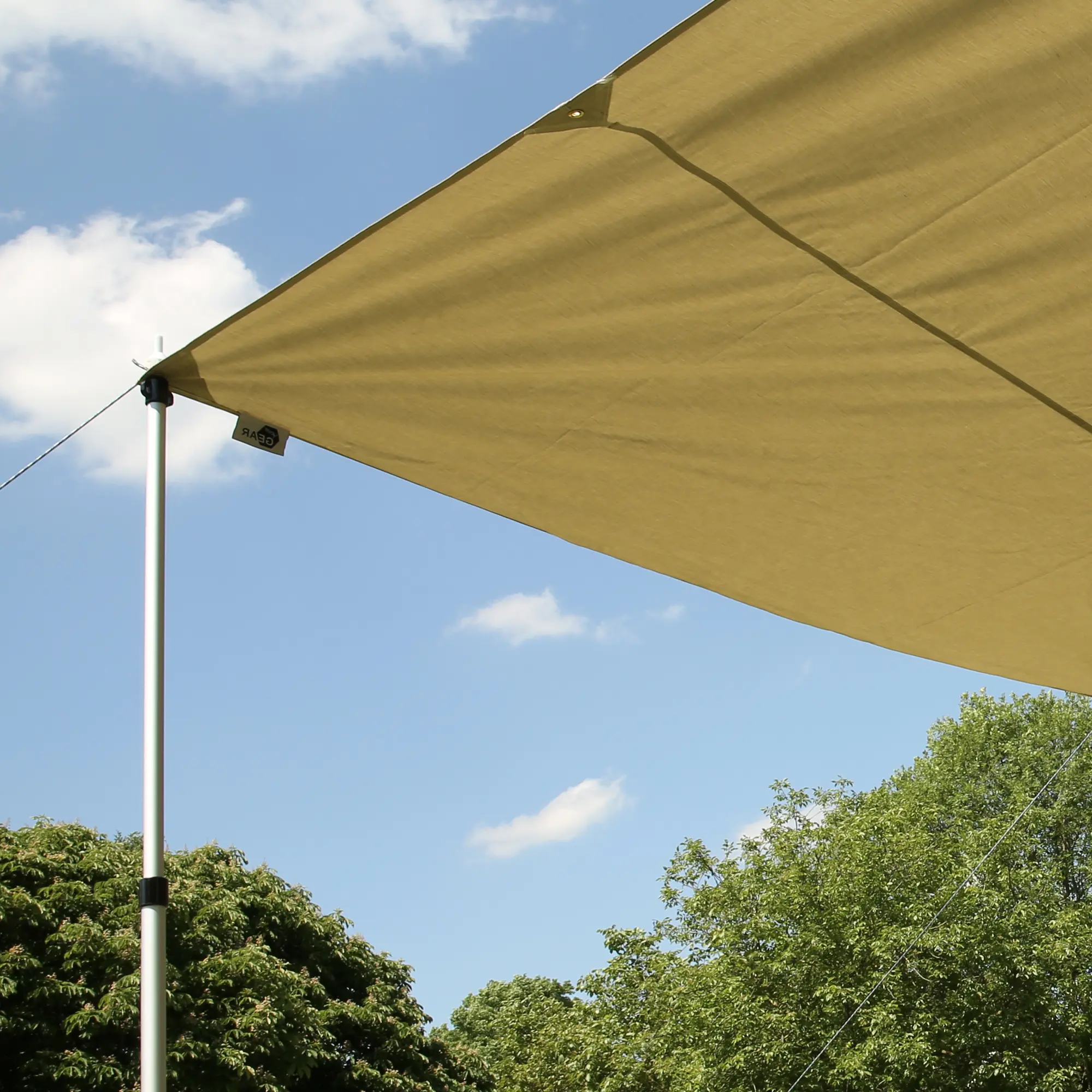 Tenda da sole your GEAR Motorhome Cotton Tarp TC 260 x 240 cm in tessuto misto cotone, fissata con pali in alluminio e corde, ideale per bus, van e auto, offre ombra all’aperto su sfondo cielo e alberi.