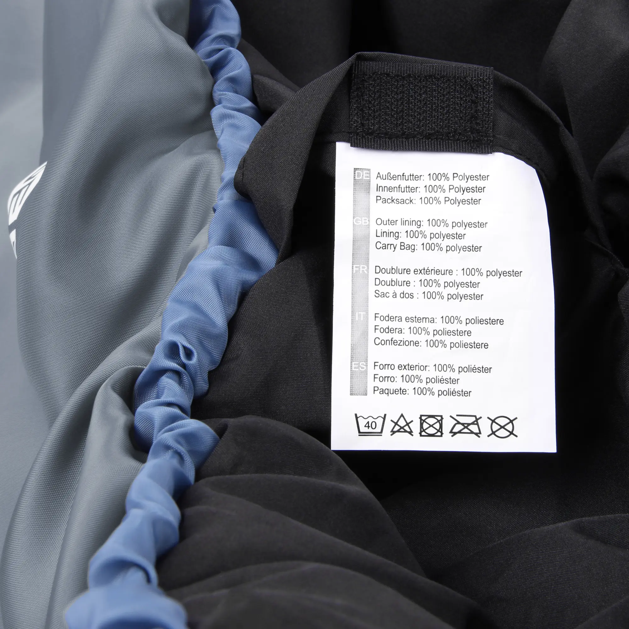 Etichetta interna del sacco a pelo yourGEAR Sirocco blu e grigio, con specifiche materiali in diverse lingue e istruzioni di lavaggio, su tessuto imbottito in poliestere.