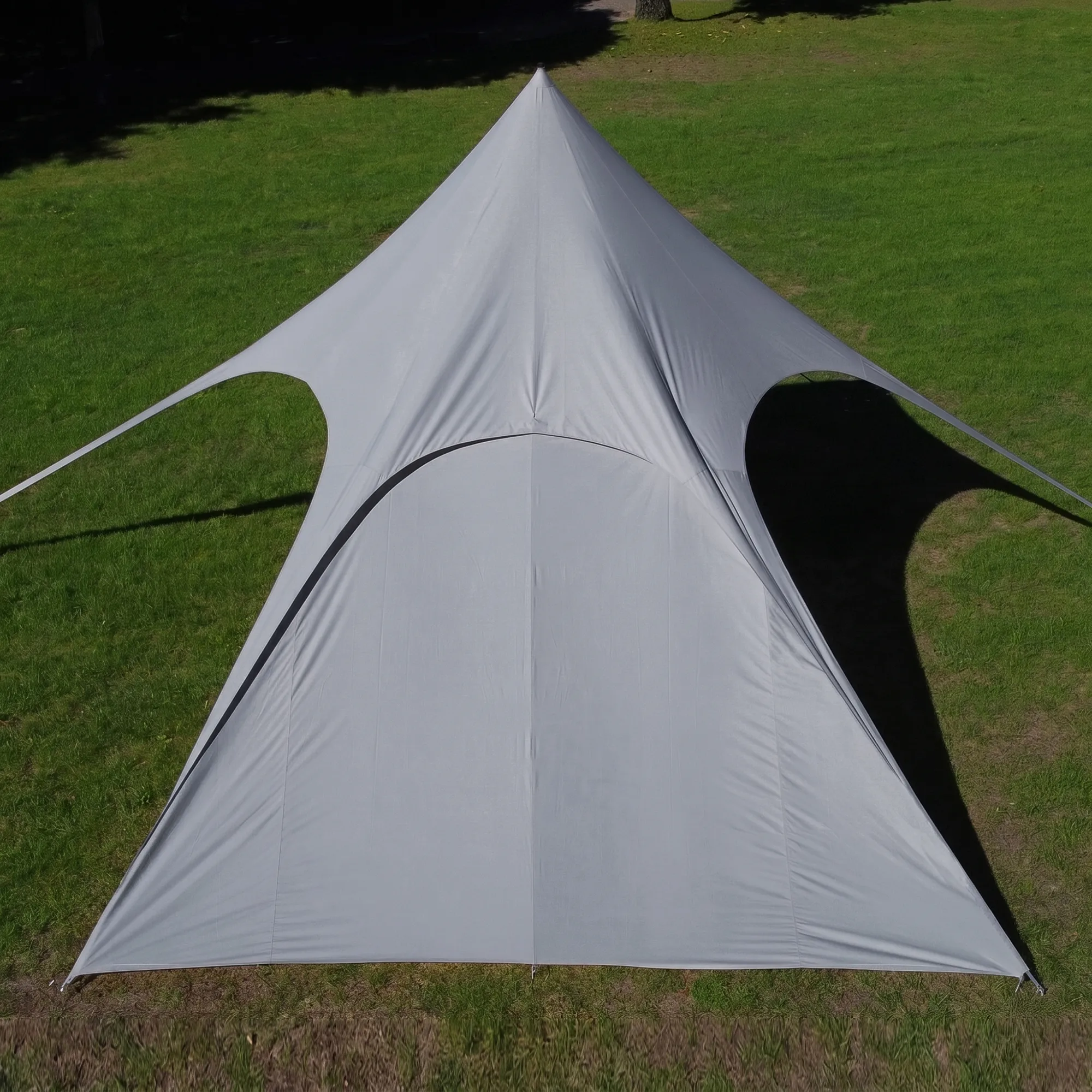 Vue aérienne d'une grande paroi latérale grise your GEAR Sonora PES pour pavillon en étoile, toile imperméable tendue en forme conique avec ouvertures arrondies aux angles, fixations aux coins et ombre portée sur pelouse.