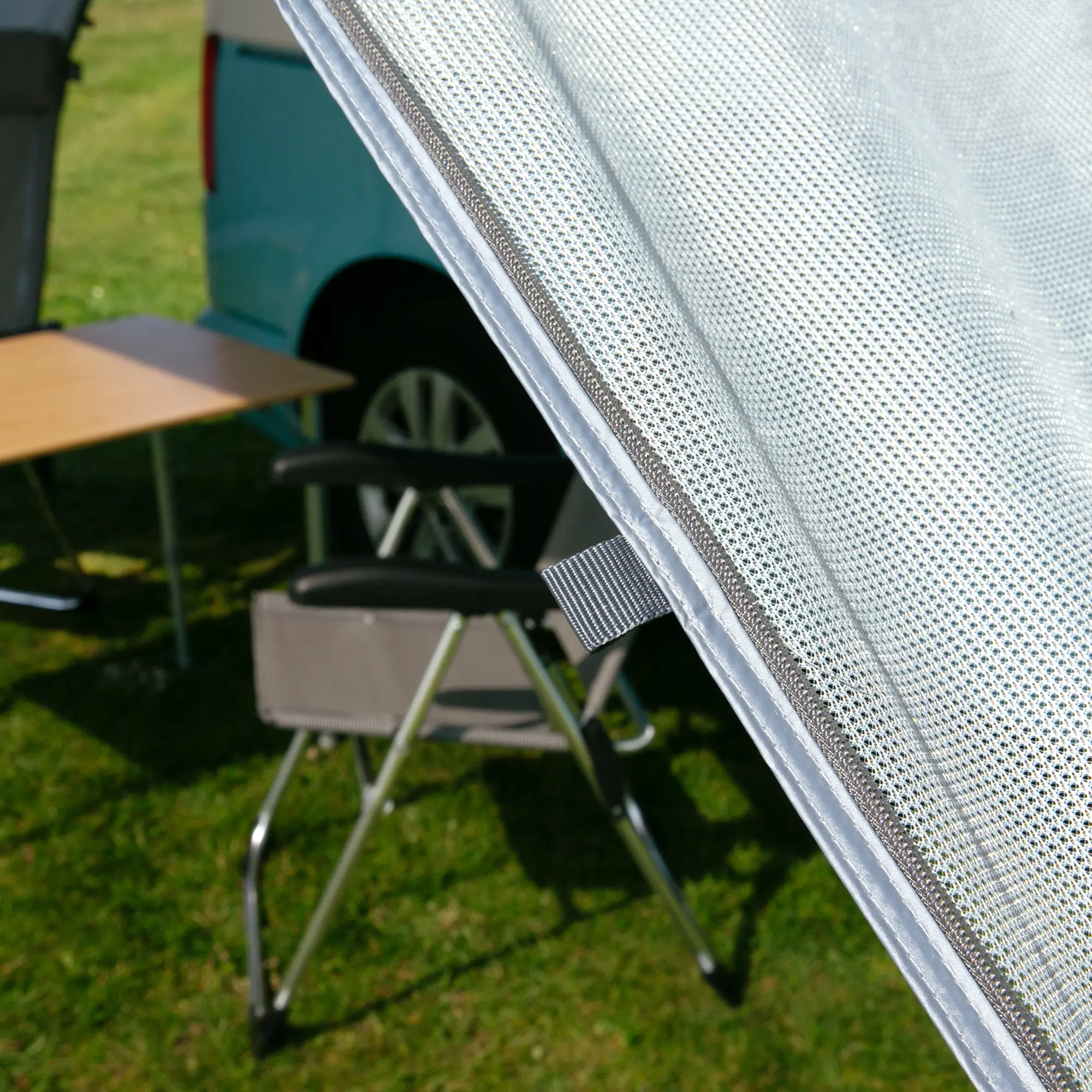 Paroi latérale your GEAR Sun + Rain Blocker pour auvent de camping-car, tissu double couche avec protection solaire ajourée et partie opaque, montage facile sur bras d’auvent, vue sur table et chaise en plein air.