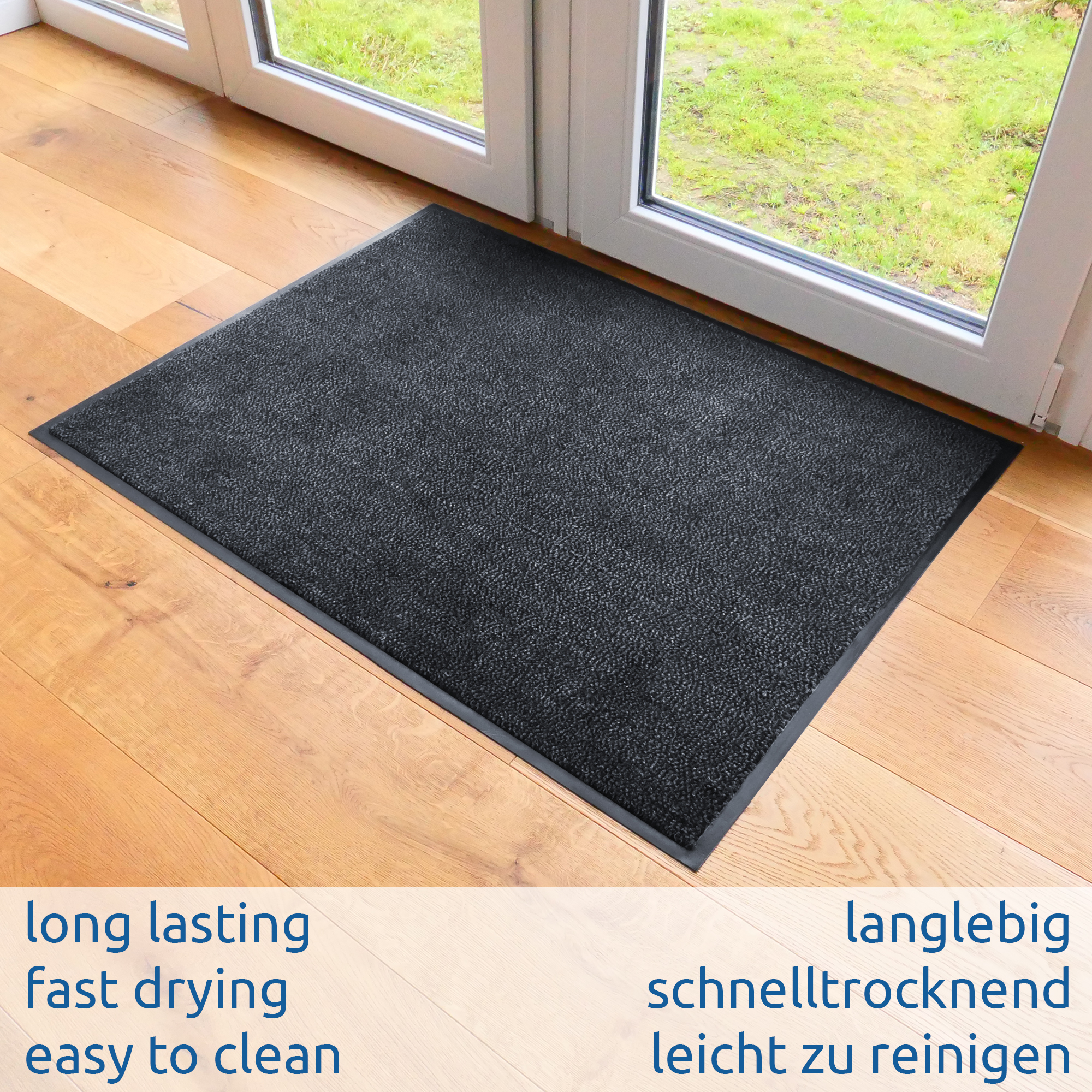 Black yourGEAR dirt-trapping mat 90x60cm with anti-slip backing and beveled edge, placed indoors by a glass door on wooden floor; dense velour pile, suitable for indoor and outdoor use, washable and fast drying.