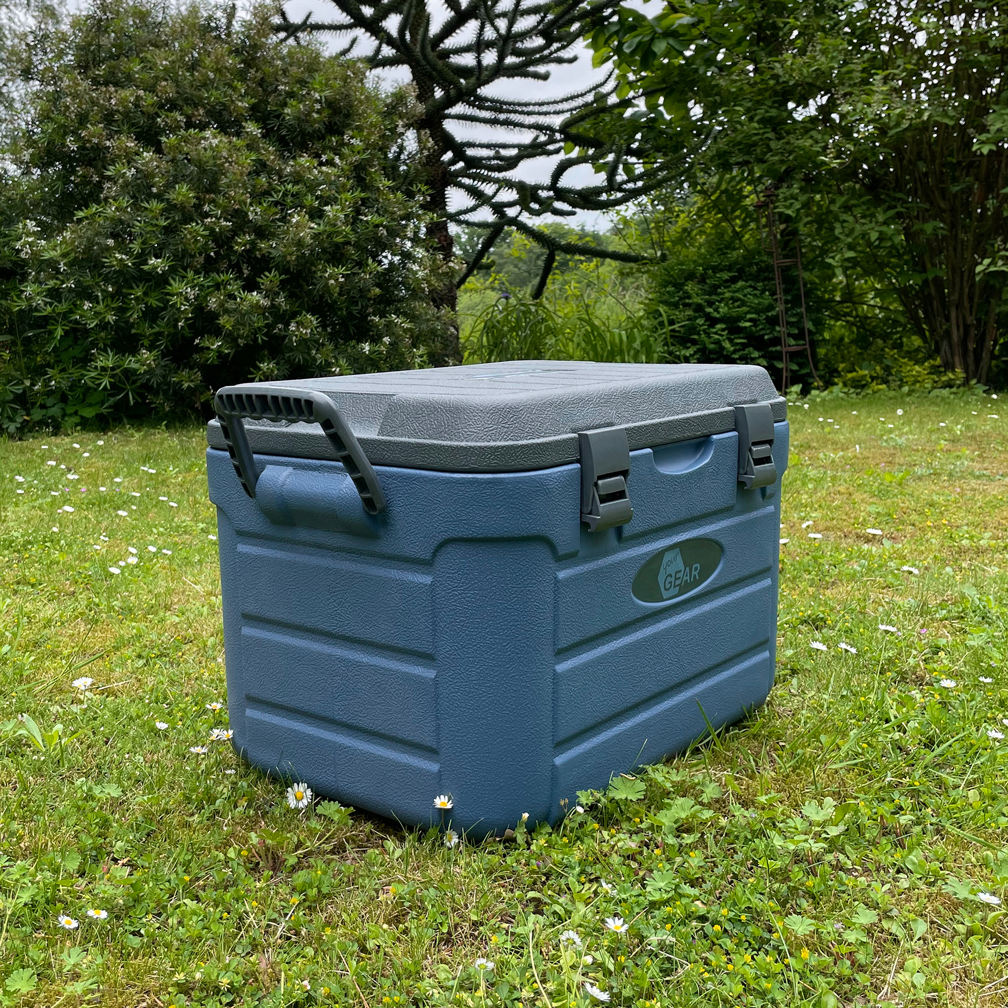 yourGEAR Coolah 30L Kühlbox, blau-grau, mit stabilem Griff und Verschlussklammern, robuste PU-Isolierung, rechteckige Form, steht auf einer Wiese im Freien. Ideal zum Kühlen oder Warmhalten von Lebensmitteln.