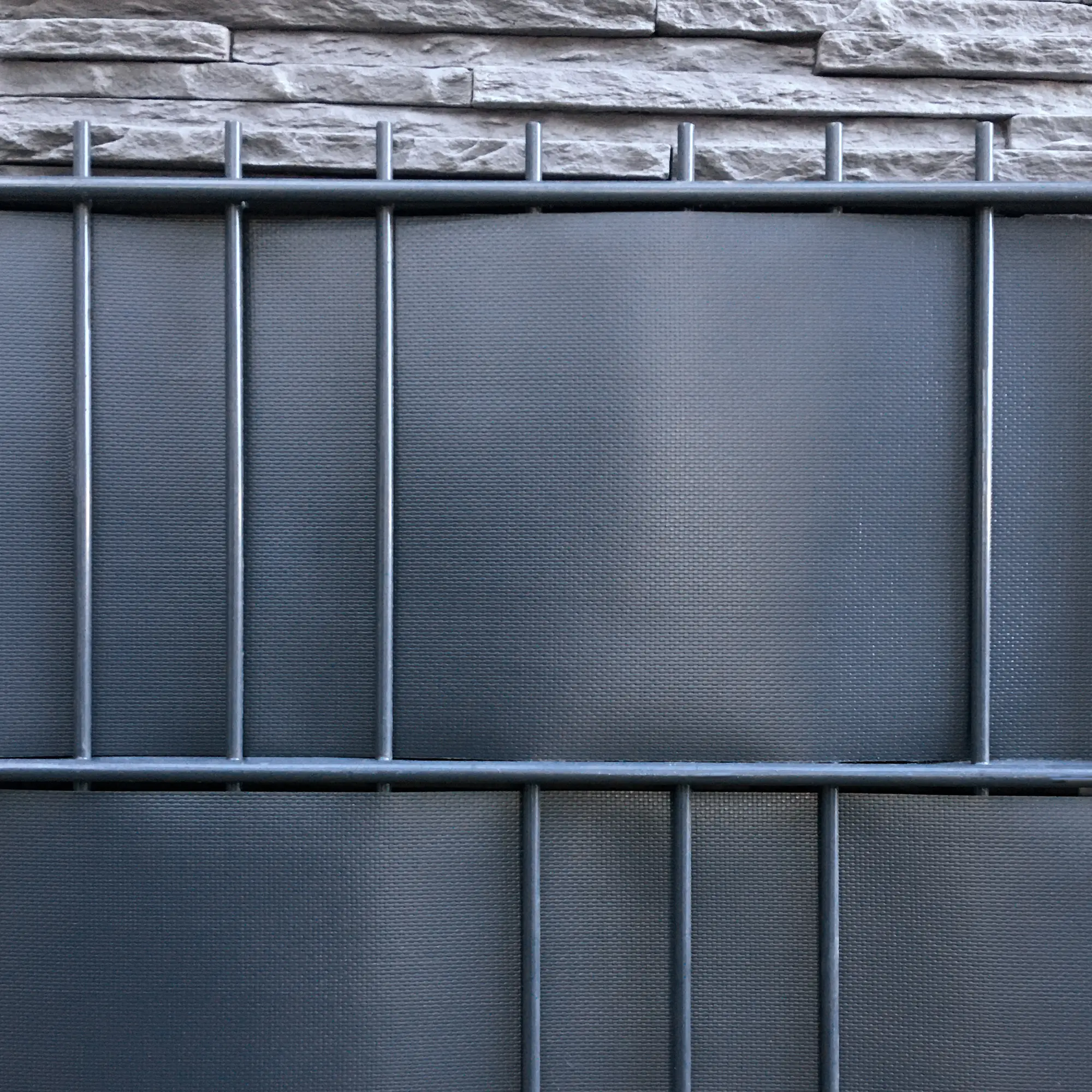 Tira de ocultación para vallas yourGEAR de PVC gris, tejido reforzado, instalada en panel de doble varilla metálica, ideal para privacidad en jardines; formato 50m x 19cm, superficie lisa, clips de fijación incluidos.