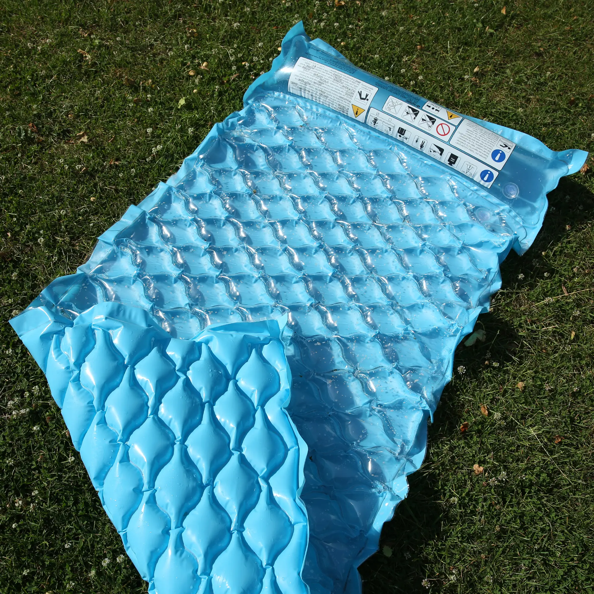 Materassino gonfiabile Jilong Wave Mat blu 218x88 cm con struttura a nido d’ape, cuscino integrato e doppia camera d’aria, ideale per piscina, spiaggia o lago, fotografato su prato verde.