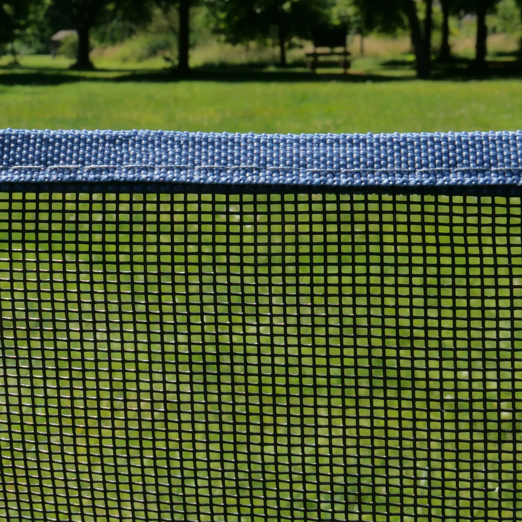 Clôture pour chien your GEAR Larino 400, filet noir à mailles fines et bordure renforcée bleue, idéale pour camping et jardin, modulaire et extensible, installée sur une pelouse verte en extérieur.