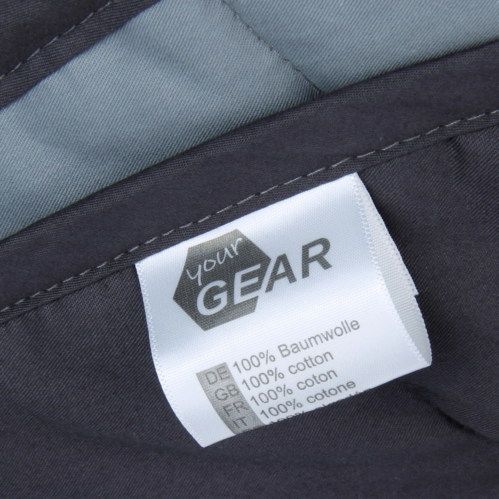 Etichetta su coperta ponderata yourGEAR Como da 6 kg, realizzata in 100% cotone, colore grigio scuro, cuciture visibili e dettagli del materiale in quattro lingue.