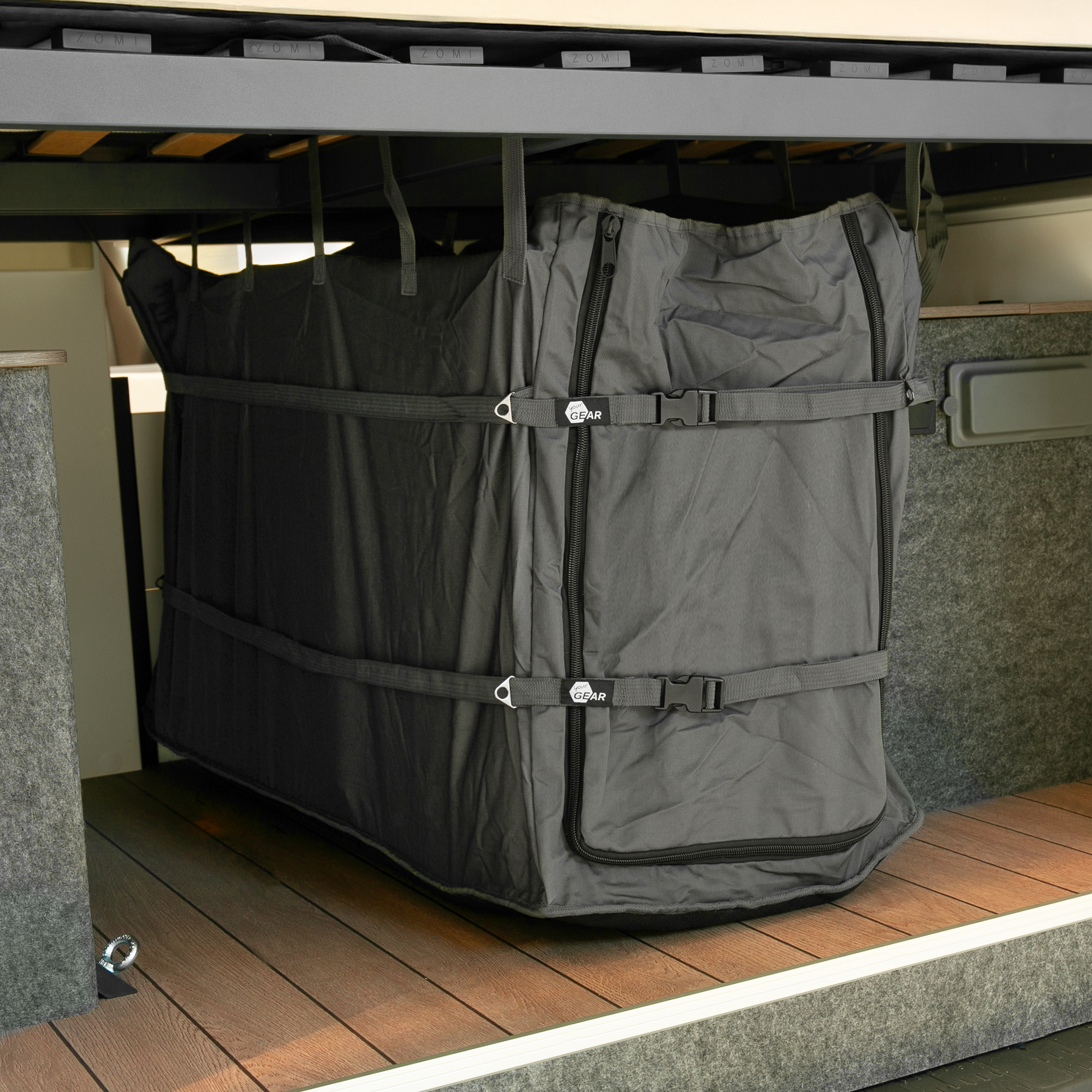 Große your GEAR Stauraumtasche Bozen in Schwarz, vertikal befestigt in der Heckgarage eines Camper-Vans, mit Gurten und Reißverschlüssen zur sicheren Aufbewahrung von Campingmöbeln und Zubehör.