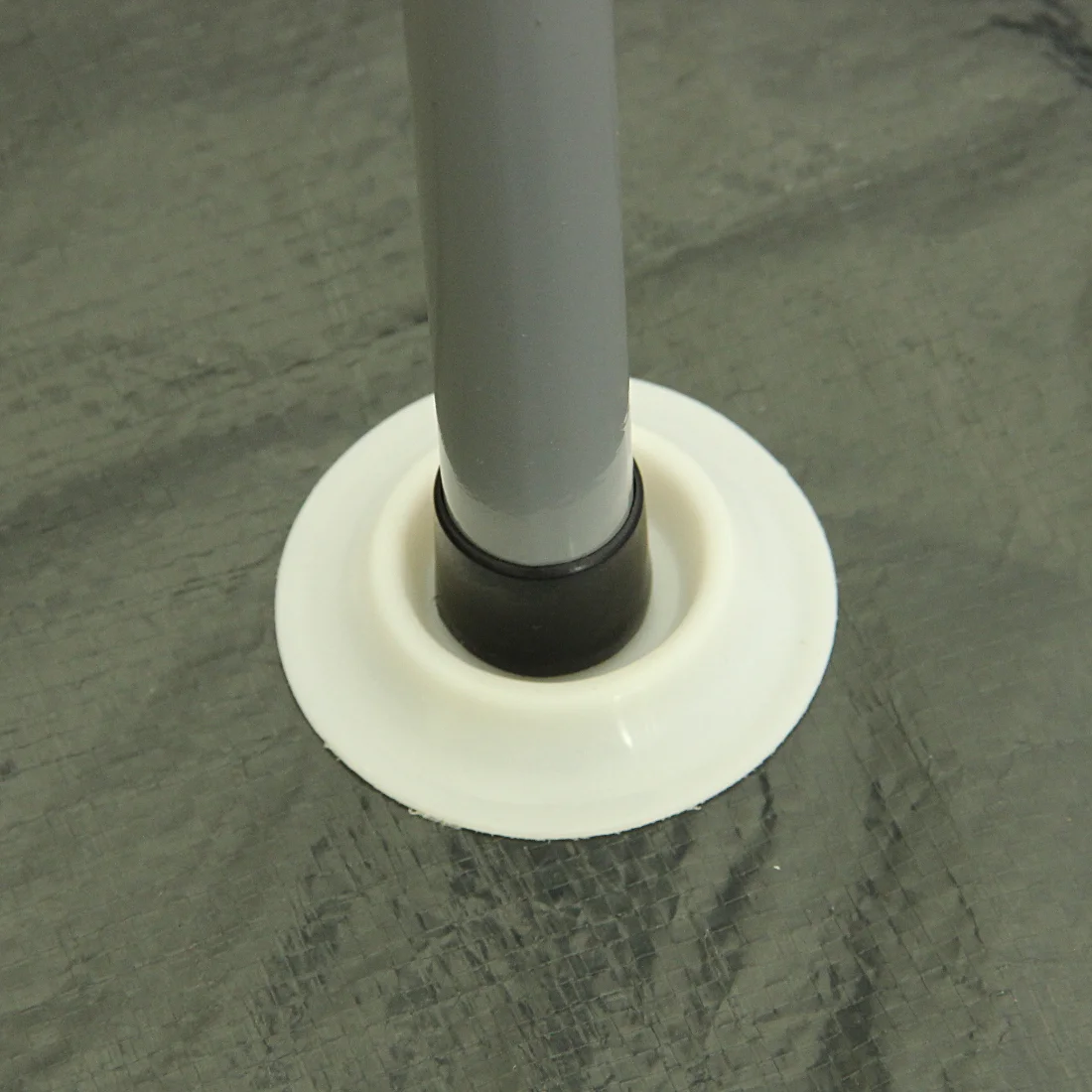 Detailaufnahme des 10T Mungaroo 3 Campingzelts: graues Zeltgestänge mit schwarzem Fuß in weißem Kunststoffhalter auf wasserdichter, strukturierter Zeltbodenplane. Perfekt für Outdoor und Camping.