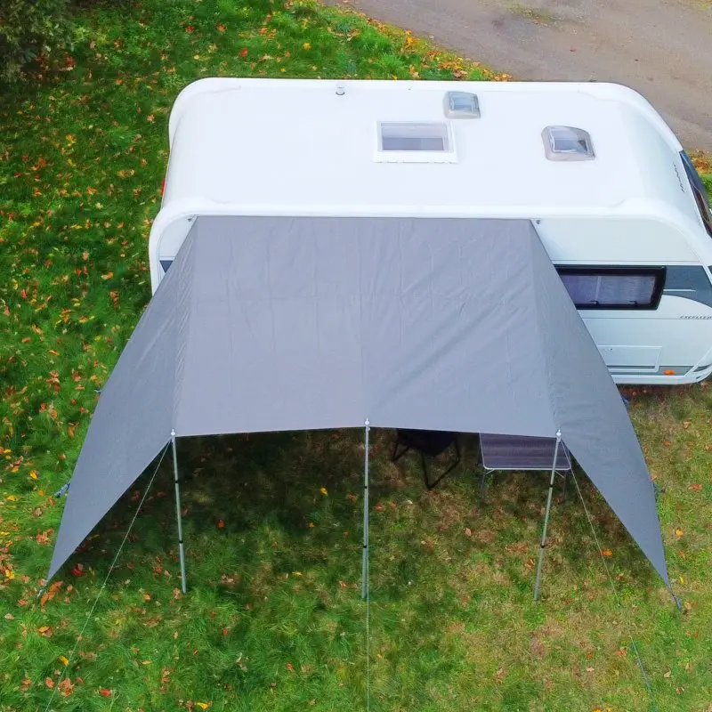 Graues your GEAR Teramo 400 Sonnendach mit Seitenwänden am Wohnwagen, aufgestellt mit Aluminium-Teleskopstangen auf einer Wiese; bietet UV 50+ Schutz und Wetterschutz für Caravan oder Wohnmobil.