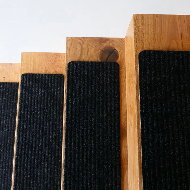 Tapis de marche yourGEAR auto-adhésif gris 76x20 cm sur marches en bois, surface antidérapante à structure nervurée, coins arrondis, dessous TPR pour fixation sans colle, pose et retrait faciles.