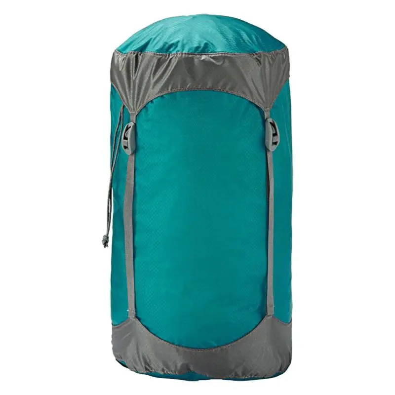 Saco de compresión Trekmates 8L en nylon azul con detalles grises, cuatro correas de compresión, cierre de cordón y tapa, ideal para guardar sacos de dormir, resistente y compacto.