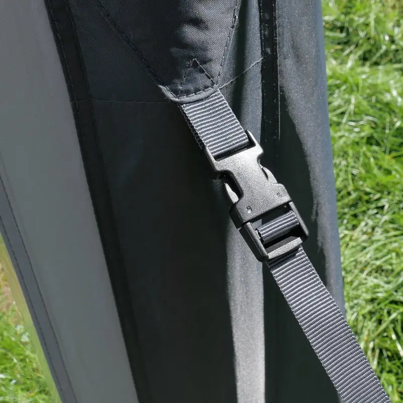 Detalle de la hebilla de sujeción y correa ajustable del avancé hinchable your GEAR Manarola Air Camper, tejido resistente en negro y gris, ideal para furgonetas y autocaravanas. Césped verde de fondo.