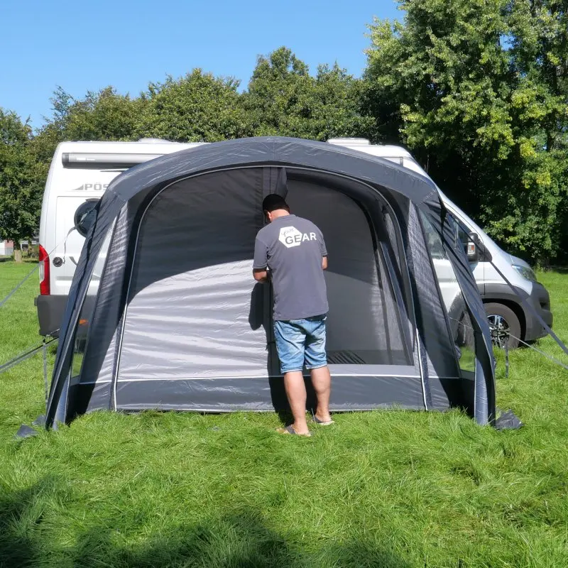 Avance de un toldo hinchable your GEAR Manarola Air Camper gris montado junto a una furgoneta camper, con puerta lateral y ventanas, ideal para vehículos de 230-270 cm de altura en camping.
