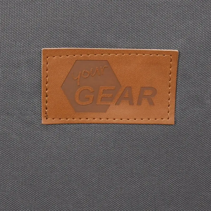 Close-up of the your GEAR Frontera dog car seat label, showing a brown leather patch with embossed logo on durable, dark grey fabric. Ideal for SEO: dog car seat, your GEAR, label, durable material.