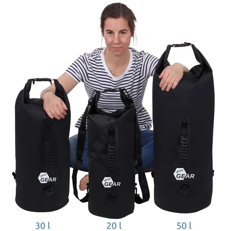 yourGEAR Dry Bag 50L wasserdichter Rucksack, schwarz, mit Rollverschluss, Schultergurten, Tragegriff und Ventil, neben 20L und 30L Varianten, stehend vor einer Person, robustes 500D PVC Material.