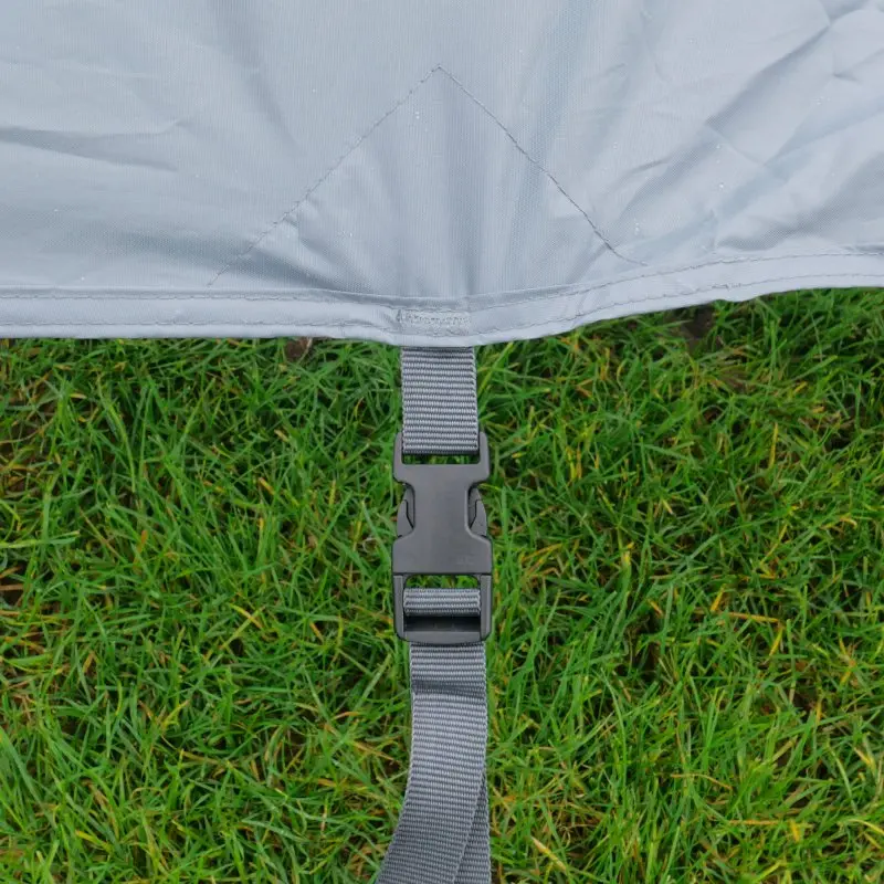 Vue rapprochée de la paroi panoramique your GEAR 2,4 x 2 m pour auvent, montrant le tissu imperméable gris, couture renforcée et sangle avec boucle de fixation, posée sur de l’herbe verte.