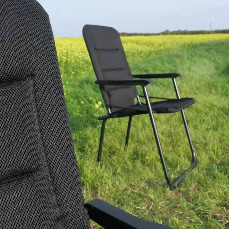 Chaise de camping your GEAR Lipari 3D Mesh noire, dossier haut, rembourrage confortable, structure en aluminium léger, tissu à séchage rapide, accoudoirs noirs, installée sur une pelouse verte en plein air.
