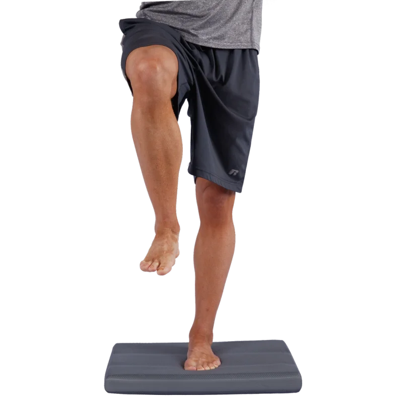 Uomo in equilibrio su un cuscino da bilanciamento Spirit Balance-Block XL grigio, rettangolare, dimensioni 50x40x6 cm, ideale per yoga, fitness e allenamento della stabilità articolare.