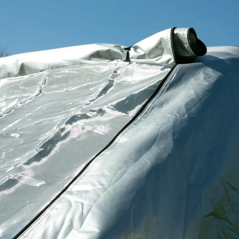 Sonnenschutzmatte your GEAR Sanremo Plus für VW T5/T6/T6.1, silbernes Thermocover mit Sichtfenster und Reißverschluss, reflektierende Oberfläche, Schutz vor Sonne und Hitze, auf Fahrzeugdach montiert.