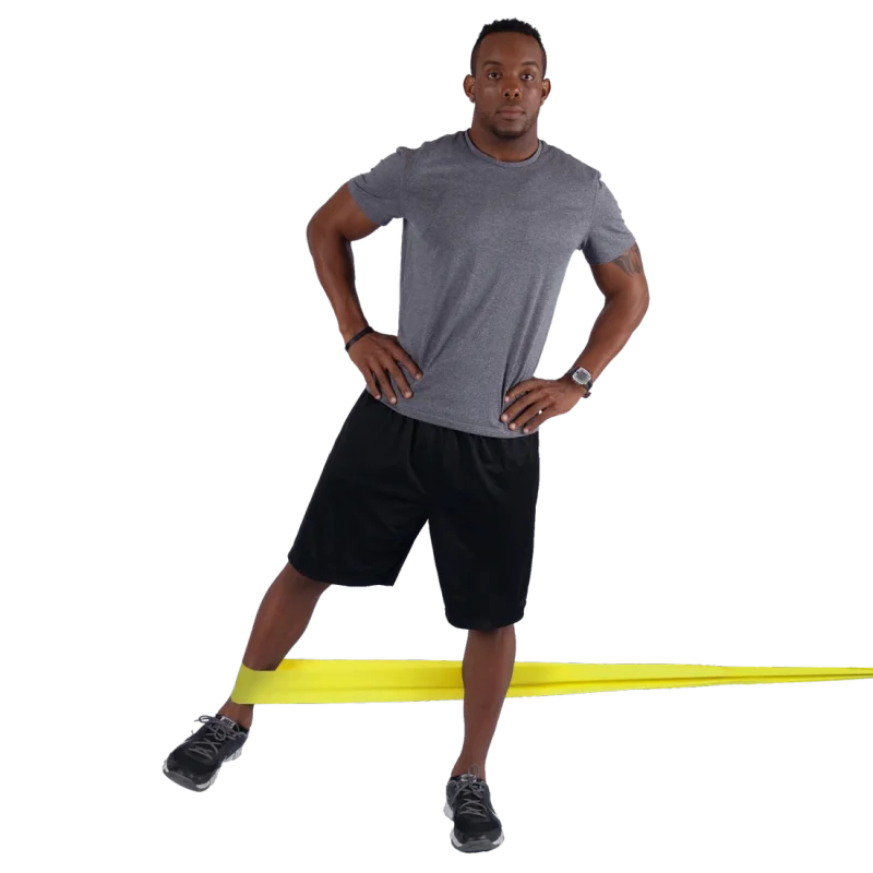 Man exercising with a yellow Spirit Fitness Band 183x10 cm, demonstrating resistance training; latex-free band stretched around legs for lower body workout; suitable for strength, rehab, and flexibility exercises.
