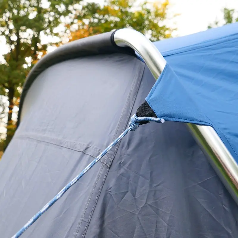 Detailaufnahme des your GEAR Sharki 330 Wohnwagen Sonnendachs: Blaues Vorzelt mit stabilem Alugestänge, gespannter Abspannleine und seitlichem Anschluss am grauen Wohnwagen, ideal als Reisevorzelt.