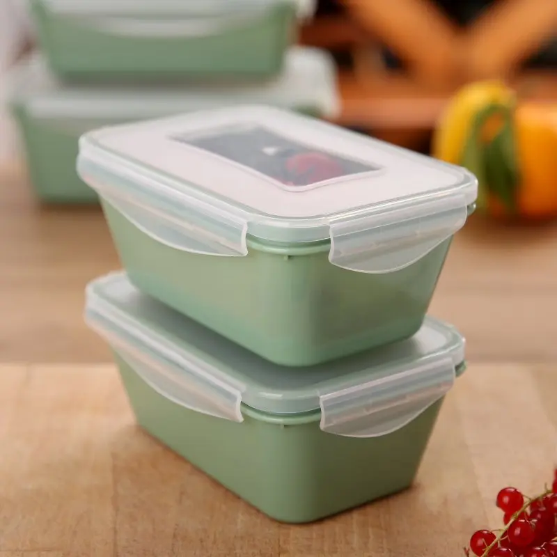 Deux boîtes de conservation empilées your GEAR Pila 700 ml vertes avec couvercles transparents et clips latéraux, posées sur une table de cuisine. Boîtes carrées, design moderne, idéales pour aliments.
