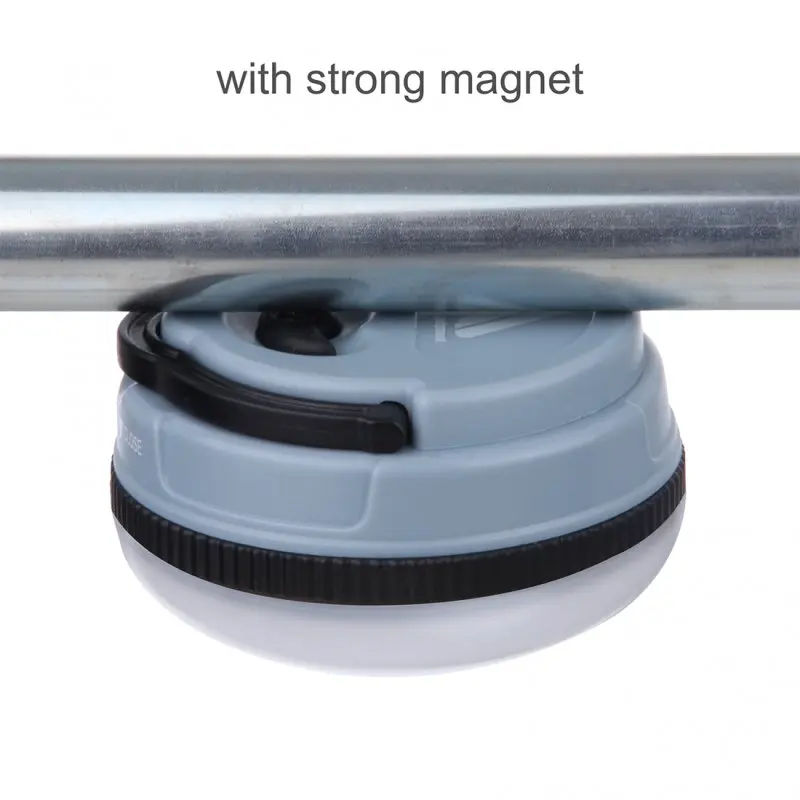 Blue 10T MCL 150 camping lamp with 150 lumens, compact round design, attached magnetically to a metal bar, black trim, visible hook for hanging, durable ABS plastic housing.