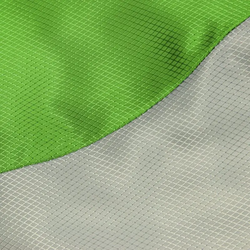 Tessuto ripstop verde e grigio visto da vicino, con motivo a griglia e cucitura curva.