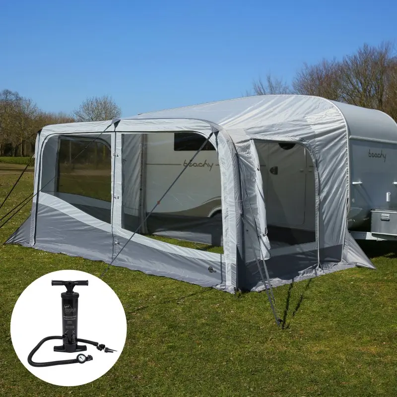 Tenda veranda gonfiabile grigia montata su una roulotte in un prato, con pompa ad aria nera mostrata nell’angolo in basso a sinistra.