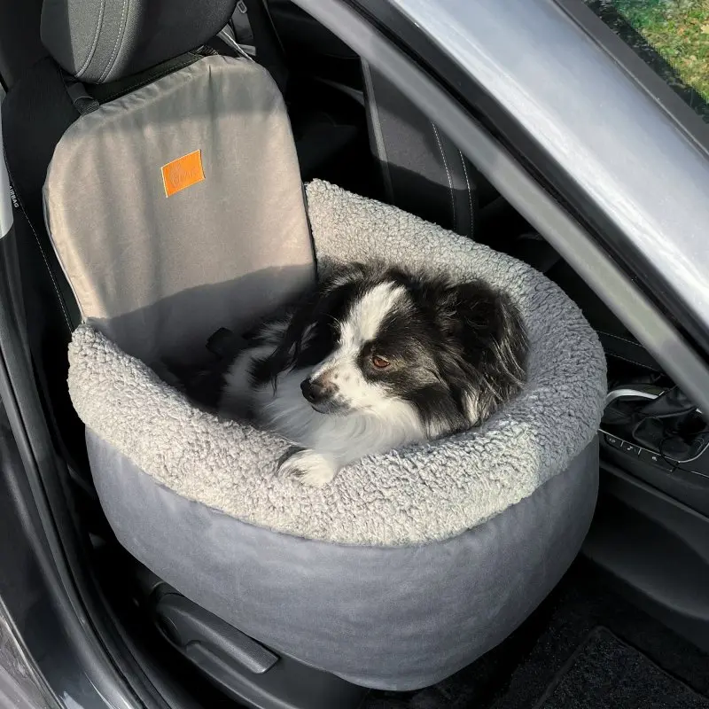 your GEAR Frontera dog car seat with soft, high sides, grey plush cover, and safety attachment on a car front seat, shown with a small black and white dog comfortably sitting inside.