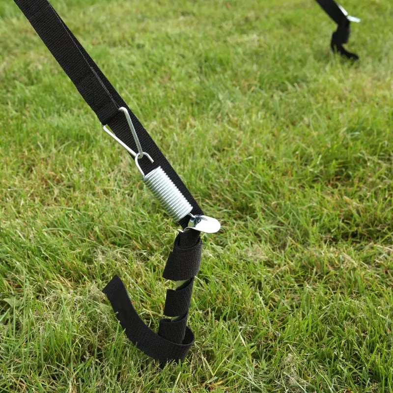 Schwarzes Sturmband mit Metallfeder und Erdhaken zur sicheren Befestigung einer Markise auf einer Wiese, Teil des your GEAR Storm Set Markisen-Sturmsicherungssets für Camping und Caravan.