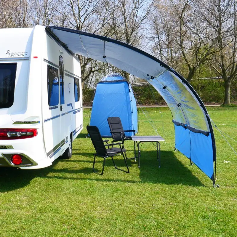 Chaise de camping your GEAR Lipari 3D Mesh noire, dossier haut, structure en aluminium, assise rembourrée, pliable, légère, installée devant un camping-car sous un auvent avec table pliante sur gazon.
