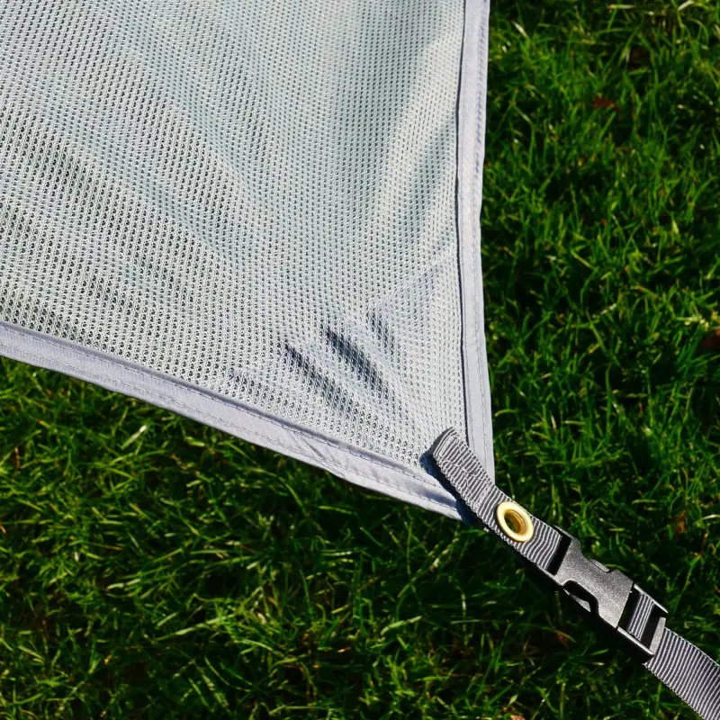 Vue détaillée du tissu maille respirant gris de la paroi avant your GEAR Capri Sun Blocker 3,7 x 2 m, avec œillet métallique et sangle de fixation, sur fond d’herbe verte. Protection solaire pour auvent camping-car.