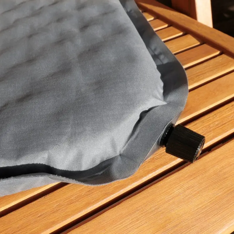 Cojín térmico yourGEAR autoinflable de 40x30x3,5 cm en color gris, con válvula de inflado visible, diseñado para camping, viajes o como asiento aislante sobre superficies de madera.