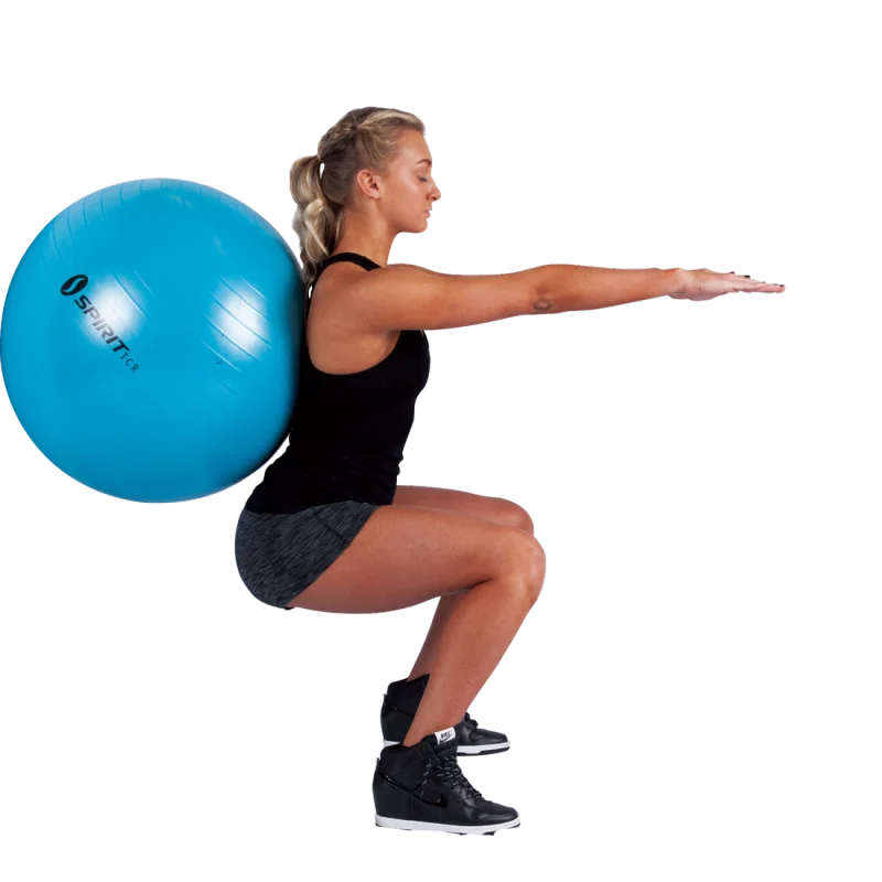 Femme effectuant un exercice de squat avec un gymball bleu Spirit TCR de 55 cm, adapté au fitness, yoga et comme siège de bureau, mettant en avant la polyvalence du ballon pour l’entraînement.