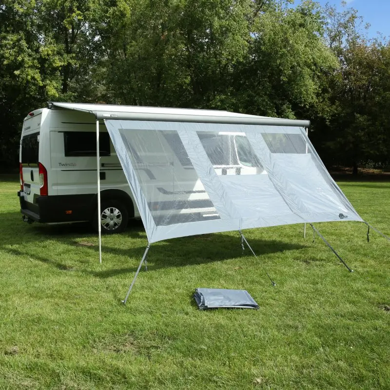 your GEAR Panorama Wall 4,3 x 2 m als transparente Vorderwand für Markisen am Wohnmobil, schützt vor Sonne, Wind und Regen, mit großen Sichtfenstern und stabilen Stangen auf einer Wiese aufgebaut.