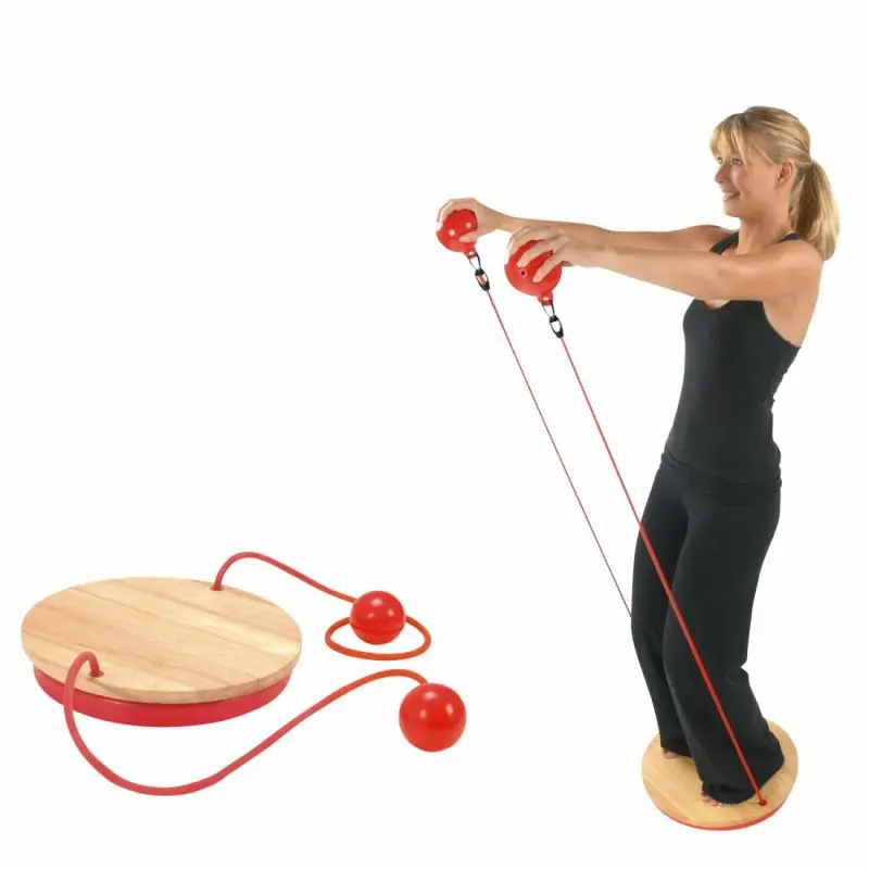 Donna in piedi su Carnegie Balance Board in legno con base rotonda, utilizza due palle rosse collegate a tubi di resistenza per l’allenamento; il set è mostrato anche separatamente a sinistra.
