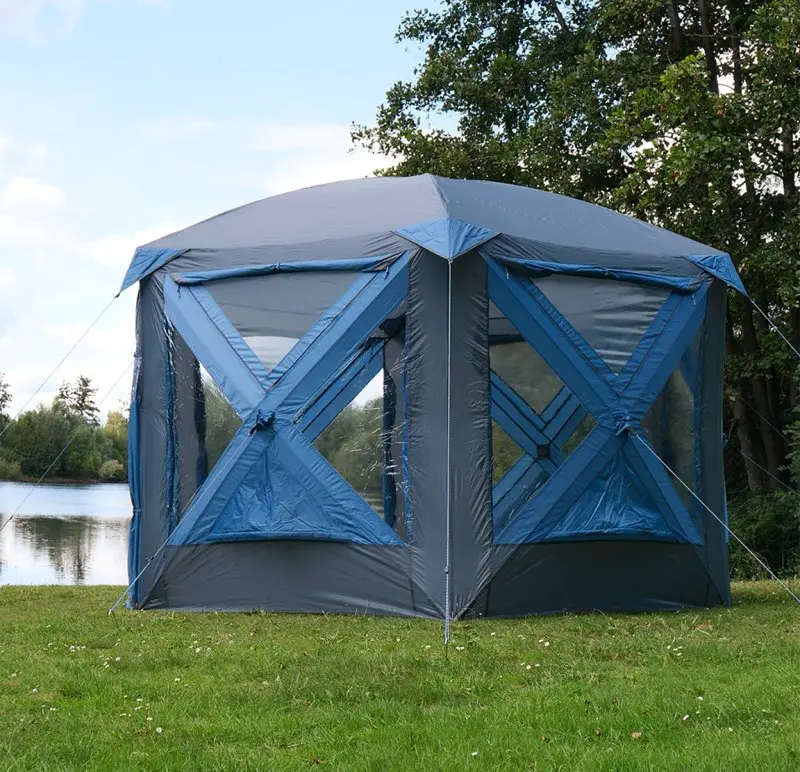 Tente pavillon yourGEAR Levanzo 8,5 m², structure pop-up, pour 4 à 6 personnes, couleur bleu et gris, grandes fenêtres transparentes, installée sur pelouse près d’un lac, adaptée camping et jardin.