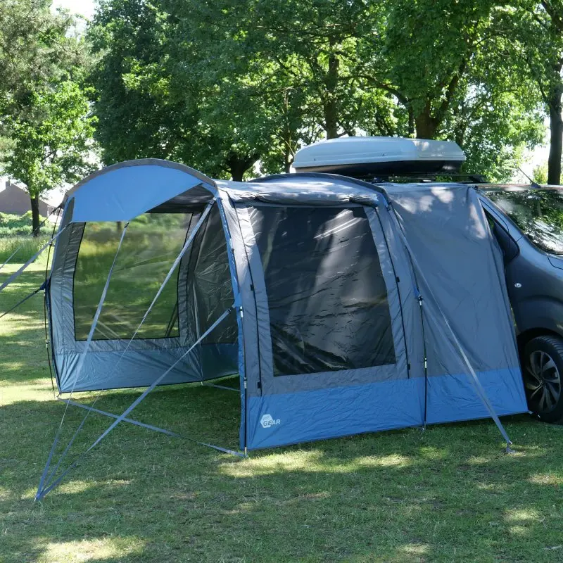 Auvent your GEAR Panarea 320 gris et bleu, fixé à un van, grande surface de vie, fenêtres transparentes, tissu imperméable, protection UV 50+, structure légère, installé sur gazon en plein air.