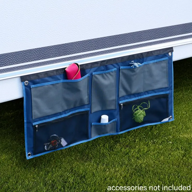 your GEAR Caravan Organizer Wide, blue and grey hanging shelf with 6 pockets, attached to caravan exterior, ideal for tents or awnings, shown with various small items inside. Accessories not included.