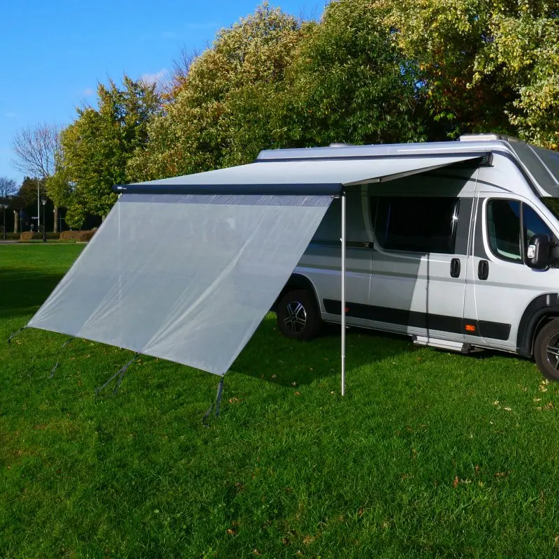 Vorderwand your GEAR Capri Sun Blocker 2,8 x 2 m an Markise eines Wohnmobils montiert, lichtdurchlässiges Gewebe als Sonnen- und Sichtschutz, mit Bodenabspannung, auf grünem Campingrasen.