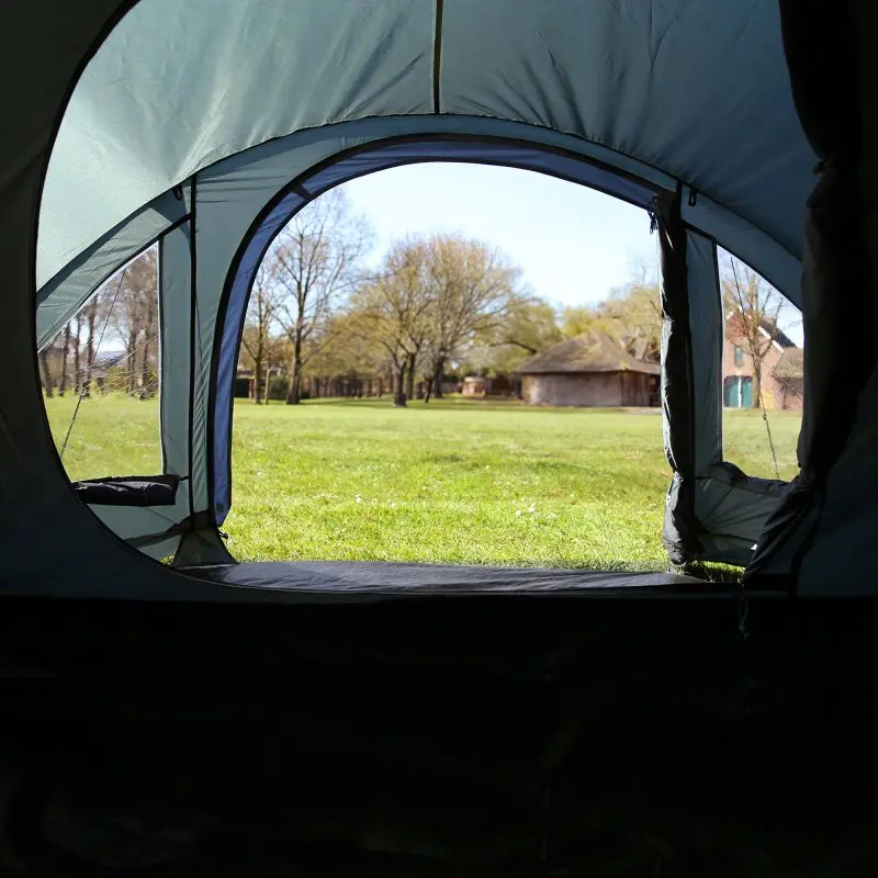 Vue depuis l’intérieur du your GEAR Monza tente dôme 4 personnes, avec sol du vestibule, grandes fenêtres transparentes et vue sur un pré vert, idéale pour le camping, protection UV50+, imperméabilité 3000 mm.